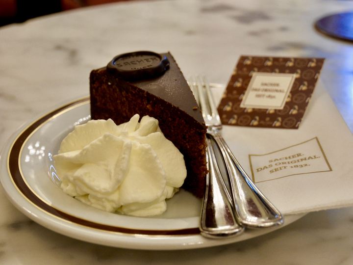 A slice of Sachertorte with whipped cream on a plate in Vienna