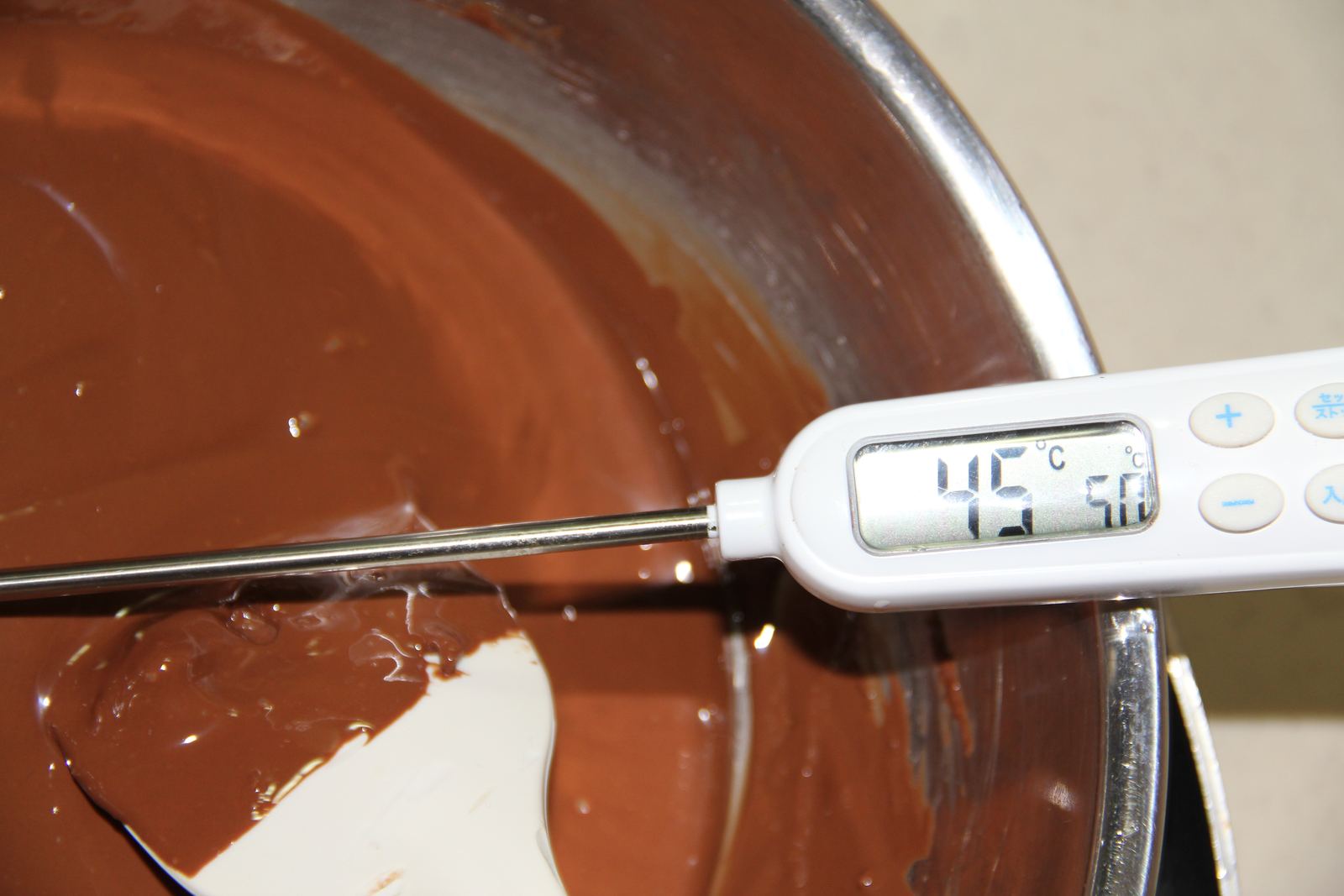A thermometer in a bowl of melted chocolate during tempering